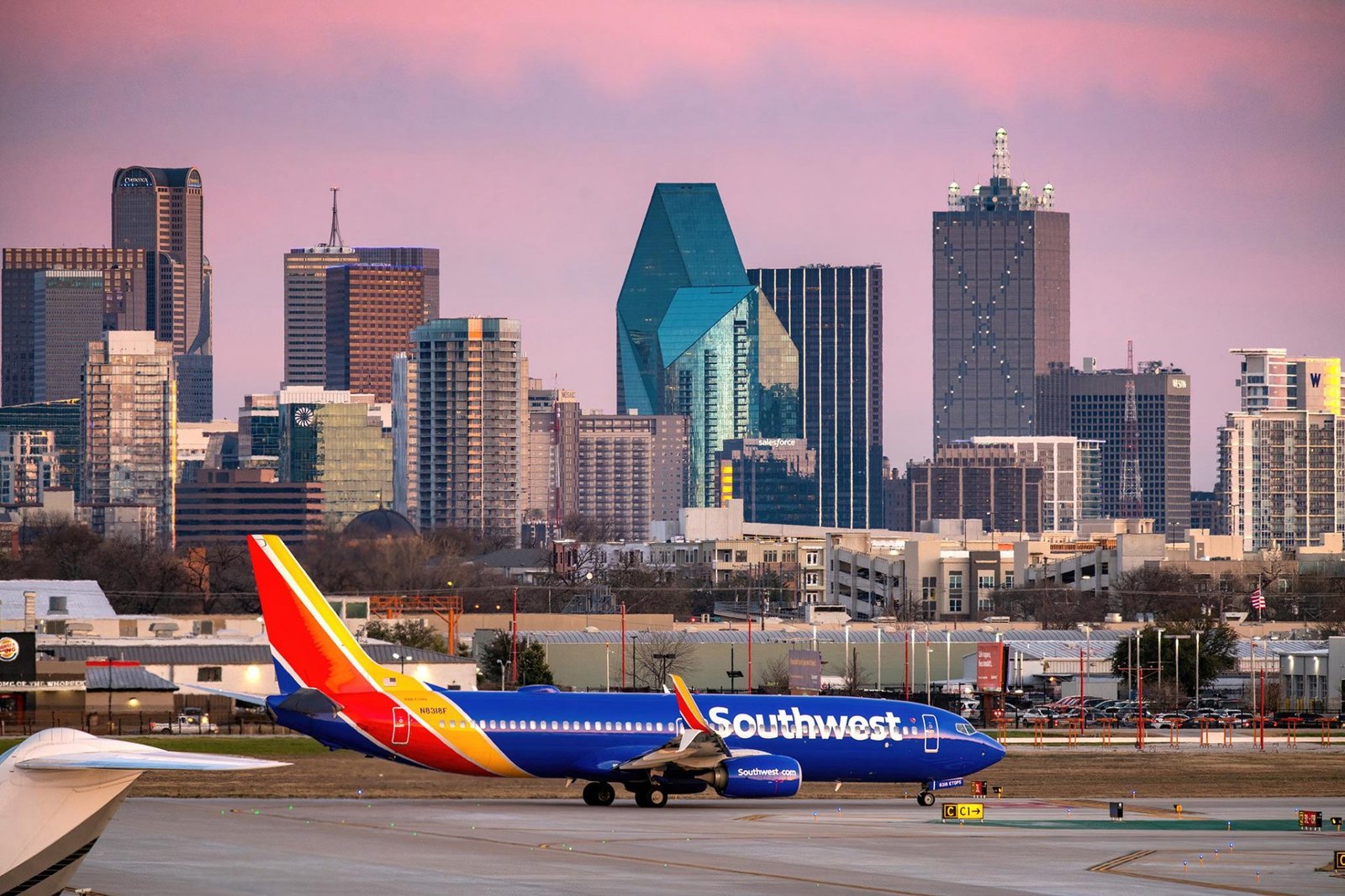 A Southwest Airlines Boeing 737 on the taxiway at Dallas Love Field with the downtown Dallas skyline at dusk